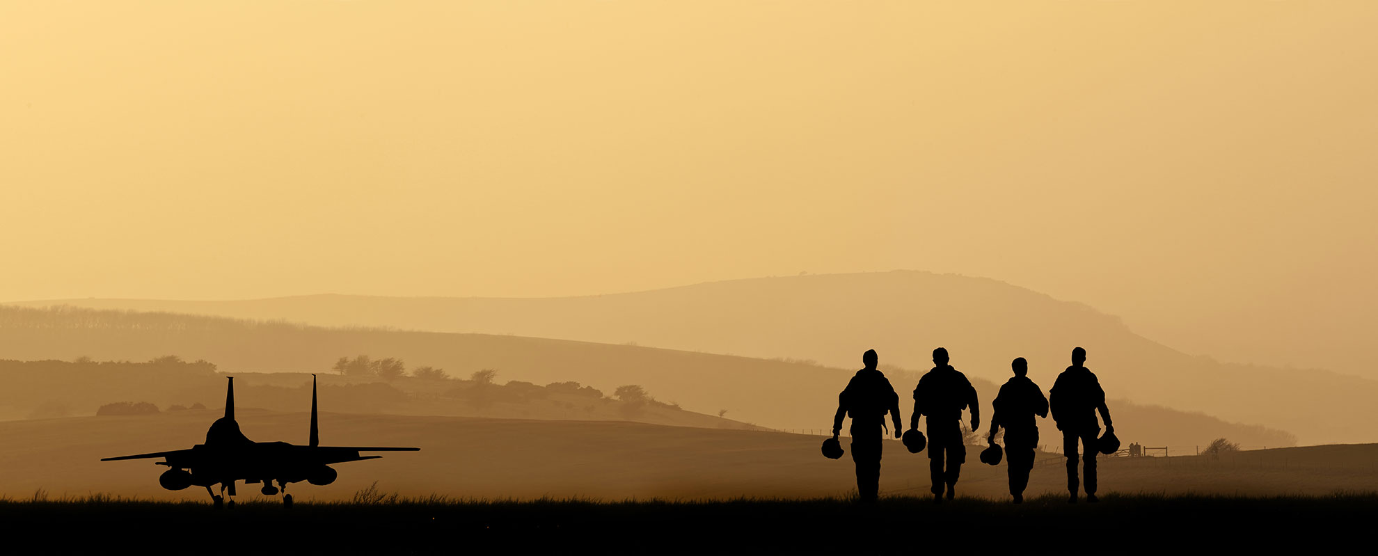Silhouette: Four pilots stroll past an aircraft.