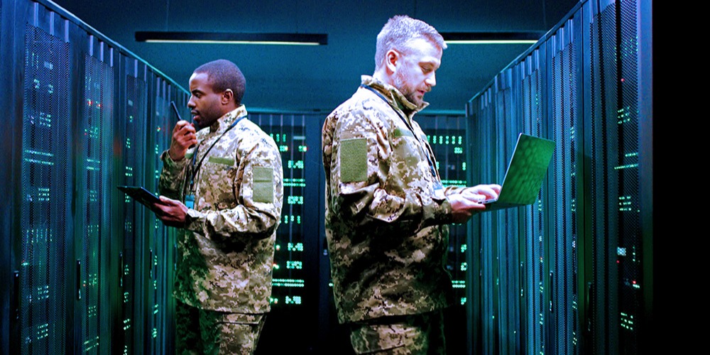 This is a photo of two servicemembers inside a military server room.