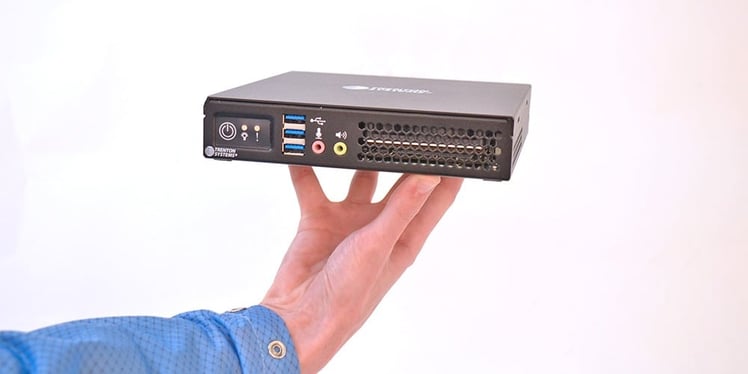 A model balances a rugged mini PC on his fingertips