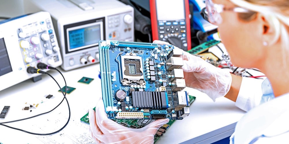 This is a photo of an electrical engineer examining a motherboard.
