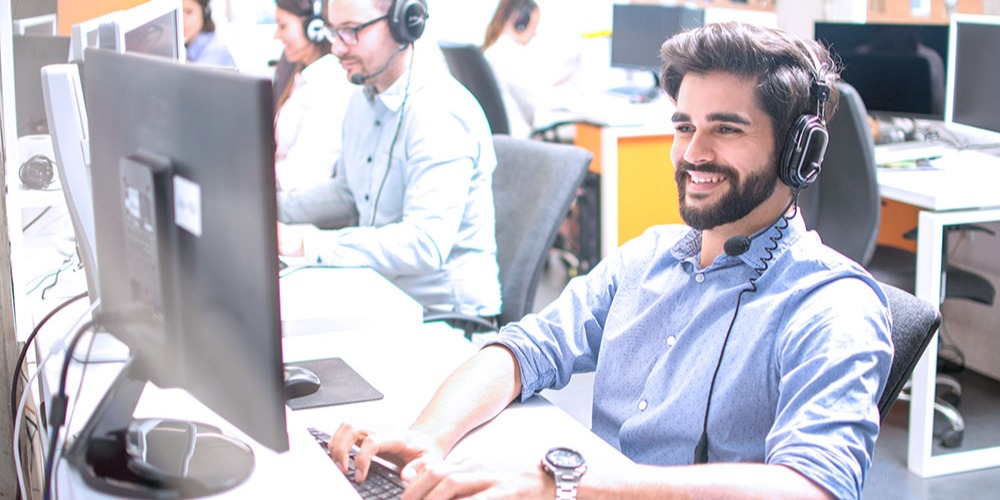 A technical support agent smiles while interacting with a customer