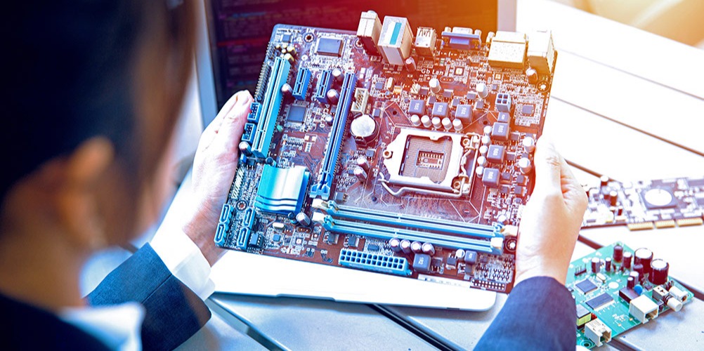 This is a photo of a person examining a printed circuit board (PCB).